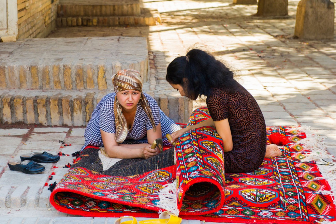 Duas mulheres uzbequestans estão trabalhando em um tapete 