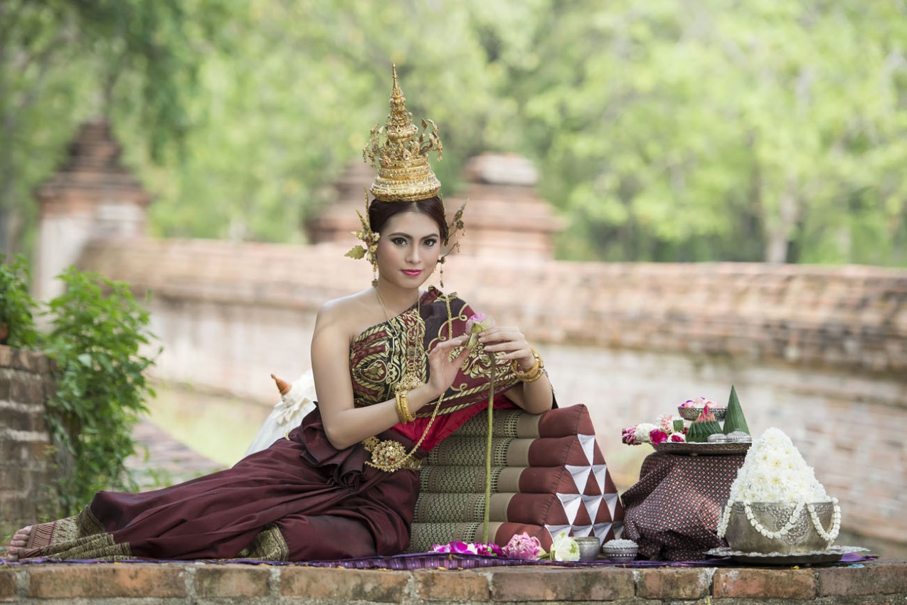 Mulher que desgasta o vestido thai típico com thai fundo do estilo do templo, cultura identidade de Tailândia