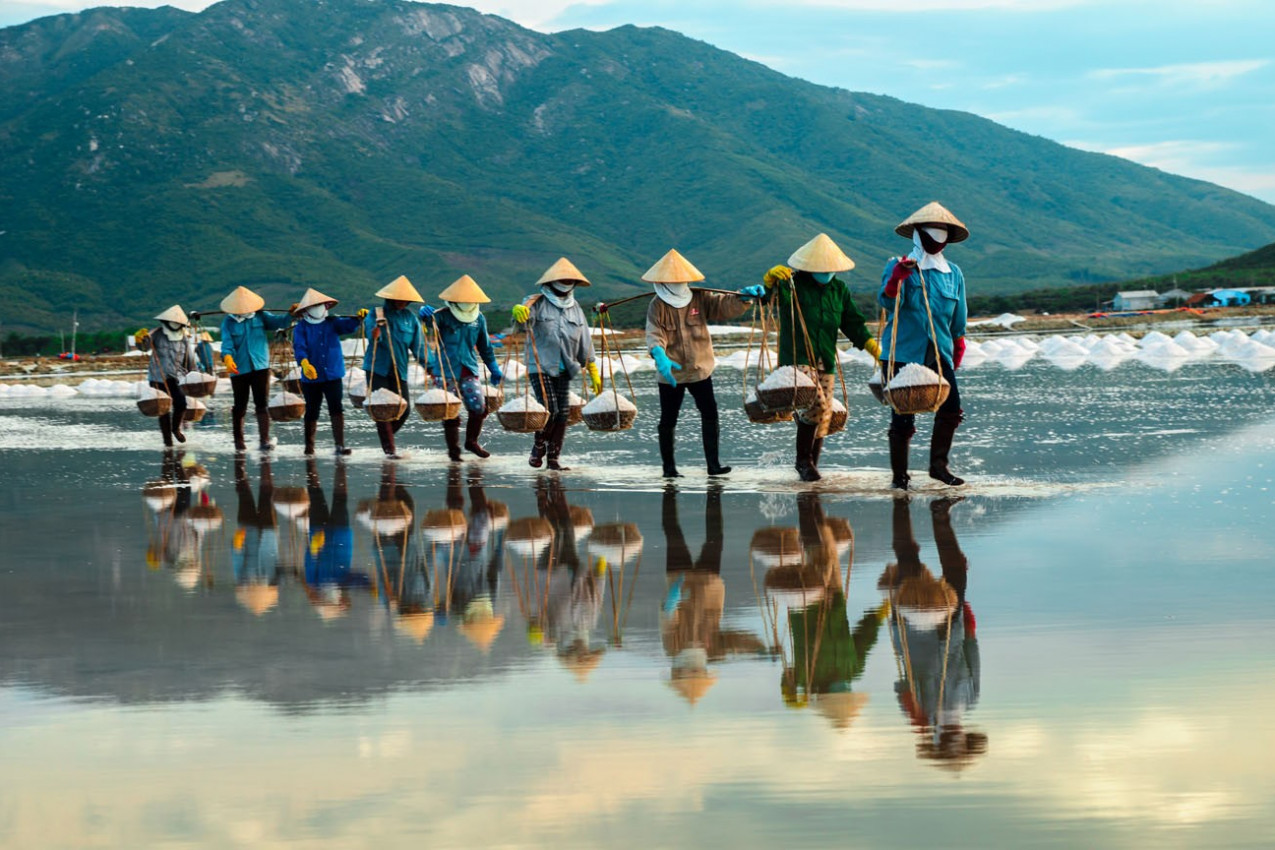 NhaTrang, Vietnam. As mulheres carregam o sal da exploração agrícola de sal para a fábrica.