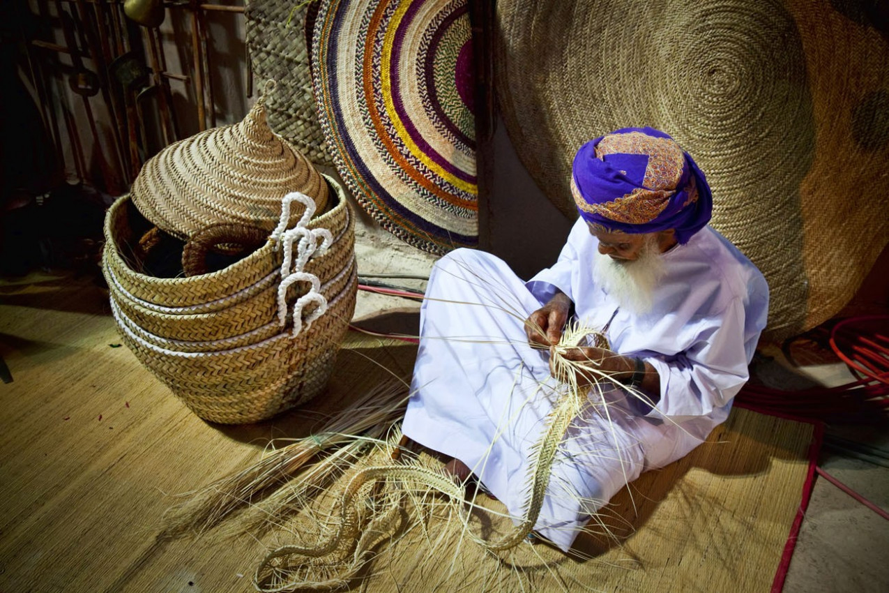 Omani demonstra um do artesanato tradicional do Omã no Festival anual Muscat